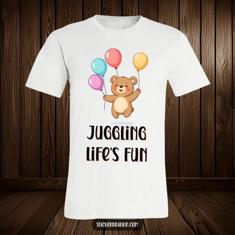 Funny t-shirt depicting a small, grinning bear expertly juggling a stack of brightly colored balloons, radiating pure fun and delight.